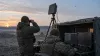 Two air-defense technicians monitor equipment at a generic field position at dawn.