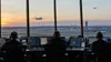 Air traffic controllers monitor a commercial airplane and a distant helicopter from an airport control room