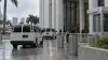 Unmarked transport vans arrive at a federal courthouse entrance in South Florida.