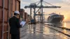 A customs analyst reviews shipping documents at a container port as cargo is unloaded.
