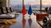 Empty international trade negotiation table with abstract red and blue desk flags, wheat, a cargo container and an aircraft component