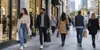 Shoppers walk through a modern American retail district in natural morning light.