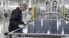 A technician inspects an unbranded solar panel on a modern factory production line.