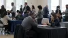 Las personas que buscan empleo conversan con los reclutadores en una feria de empleo comunitaria sin marca, a la luz natural del día
