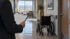 Illustrative long-term-care inspection with a blank clipboard and an empty wheelchair in a Utah facility corridor.