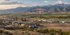 An illustrative Utah landscape where mixed-use construction and light industry transition into farmland beneath distant mountains.