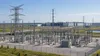 Electrical substation and transmission lines in front of a large data-center campus.