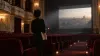 An anonymous filmmaker stands in an empty historic cinema holding an unmarked script folder.