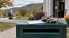 Work gloves and a blank ballot envelope rest on a drop box outside a Vermont civic building in autumn.