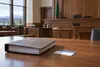 Sala de audiencias vacía, con una carpeta legal cerrada y una tarjeta de seguro médico en blanco sobre la mesa de los…