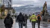 Workers cross a generic Pacific Northwest commercial and industrial district during an overcast morning shift change.