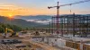 Large construction site with cranes and steel framing against West Virginia’s Appalachian hills.
