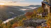 An Appalachian mountain overlook with a rustic cabin and a heritage railway curve in early autumn.