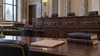 Empty wood-paneled appellate courtroom with a legal file and law books on counsel table