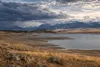 A low Wyoming reservoir beneath distant mountains and approaching storm clouds