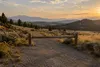 Dry sagebrush trail and unmarked wooden barrier in a Wyoming mountain landscape at sunset