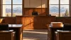 An empty wood-paneled courtroom with an unoccupied judge’s chair, blank folders on a counsel table and mountains visible through the windows.