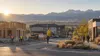 Workers arrive at a generic Wyoming construction, hospitality and office district beneath distant mountains at sunrise.