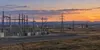 Electrical transmission lines and a modern substation stretch across the open Wyoming high plains at dusk.