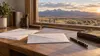 Conceptual absentee-voting envelope on a desk overlooking Wyoming high plains and mountains.