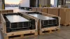 Unlabeled rack-mounted computer servers secured in shipping crates inside a freight warehouse