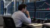 Illustrative image of a financial analyst reviewing market charts beside a data center