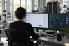 Um engenheiro de segurança monitoriza formulários web abstratos e ecrãs de atividade de rede num laboratório de tecnologia moderno.