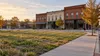 AI-generated editorial illustration of a generic Arkansas town redevelopment site with an empty brick storefront and undeveloped land; not an actual proposed district or project.