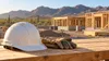 AI-generated editorial illustration of a hard hat and work gloves on a bench with a generic desert construction frame beyond; not a photograph of an actual Arizona project or layoffs.