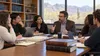 Law students and a professor discuss course materials in a university seminar room.