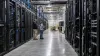 Two technicians inspect equipment in a large modern data-center server hall.