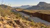 Illustrative view of a steel border barrier crossing the rugged West Texas desert in the Big Bend region