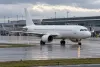 Illustrative view of an unbranded twin-engine passenger jet taxiing at a modern airport after rain.