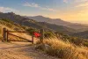 Conceptual illustration of a closed trail gate in dry coastal mountains during red-flag fire weather