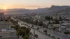 Uma vista panorâmica de uma cidade montanhosa da Etiópia ao amanhecer, com veículos militares ao longe numa estrada aberta
