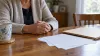 AI-generated illustrative scene of an adult's clasped hands beside blank paperwork; does not depict Tammy Nash's family.
