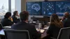 Autoridades federais e especialistas técnicos analisam visualizações de riscos de inteligência artificial numa sala de conferências em Washington.