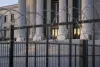 Stone courthouse seen beyond security fencing at dawn