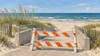 AI-generated illustration of a generic beach-access ramp behind a construction barricade; not the Silver Beach site.