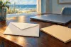 AI-generated conceptual illustration of an unmarked envelope, closed laptop and blank folder; not an actual scam message or county office.