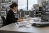 AI-generated editorial scene of an archive employee reviewing photographs and financial materials in a generic institutional photo archive.