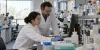 Investigadores trabalham com equipamento de laboratório num edifício de ciências da universidade.