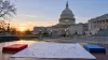 Um mapa dos Estados Unidos sem legendas, com cartões vermelhos e azuis sobre uma mesa em frente ao Capitólio dos EUA ao amanhecer