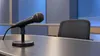 AI-generated illustration of an unbranded microphone in an empty television studio; not the actual Indiana debate set.