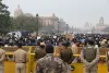 Nakatayo ang mga pulis sa likod ng mga barikada na nakaharap sa isang malaking mapayapang karamihan sa isang malawak na daanan ng distrito ng gobyerno sa New Delhi.