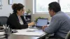 A tax preparer and client review information on a laptop in an office