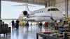 Illustrative editorial image of anonymous aircraft technicians working around a generic business jet in a Wichita-style maintenance hangar.