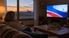A Kansas living room television displays abstract political-ad colors beside a window overlooking open prairie.