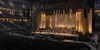 Stage crews prepare a large indoor arena for a formal performing arts ceremony.