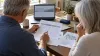 Older adults compare generic Medicare plan information at a kitchen table.